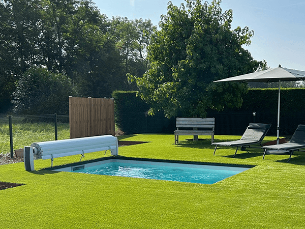 Mini-piscine coque polyester et gazon – Pool68 Mini-piscine rectangulaire dans un gazon, volet à lames blanc, transats et parasol